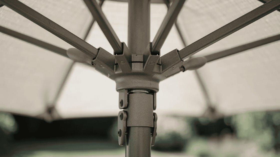Na zdjęciu znajduje się zbliżenie na mechanizm składania parasola ogrodowego, który pokazuje szczegóły jego solidnej konstrukcji oraz regulacji kąta nachylenia. Mechanizm ten umożliwia łatwe rozkładanie i składanie parasola, co zapewnia komfortowe spędzanie czasu w ogrodzie lub na tarasie.